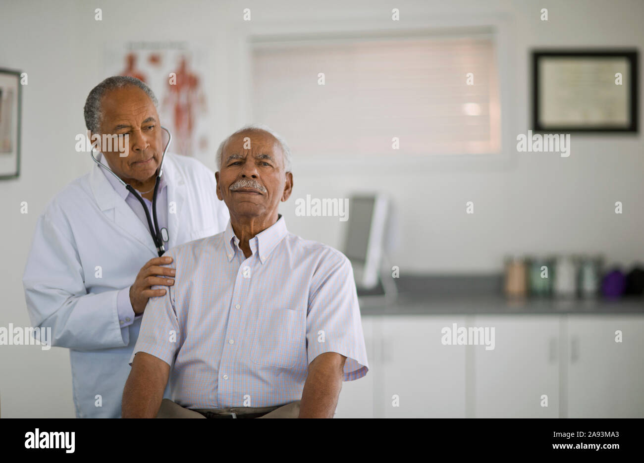 Älterer Mann seinen Herzschlag gelauscht von einem männlichen Arzt in einem Büro. Stockfoto