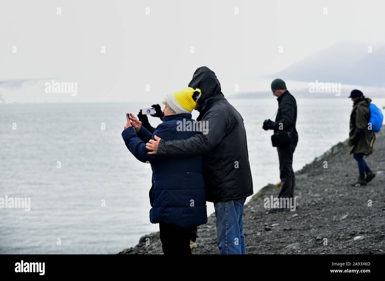 Jökulsárlón, Island. Touristen Pause entlang einer Küste zu sehen und fotografieren Eisberge vom Gletscher Vatnajökull schweben frei im See. Stockfoto
