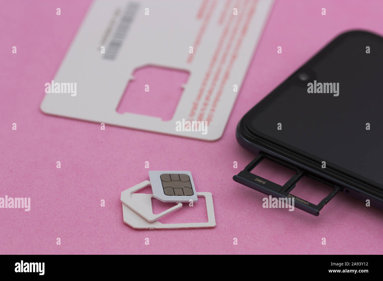 Smart Phone neben einer SIM-Karte auf das Handy Netz verbinden, auf einem rosa Oberfläche Stockfoto