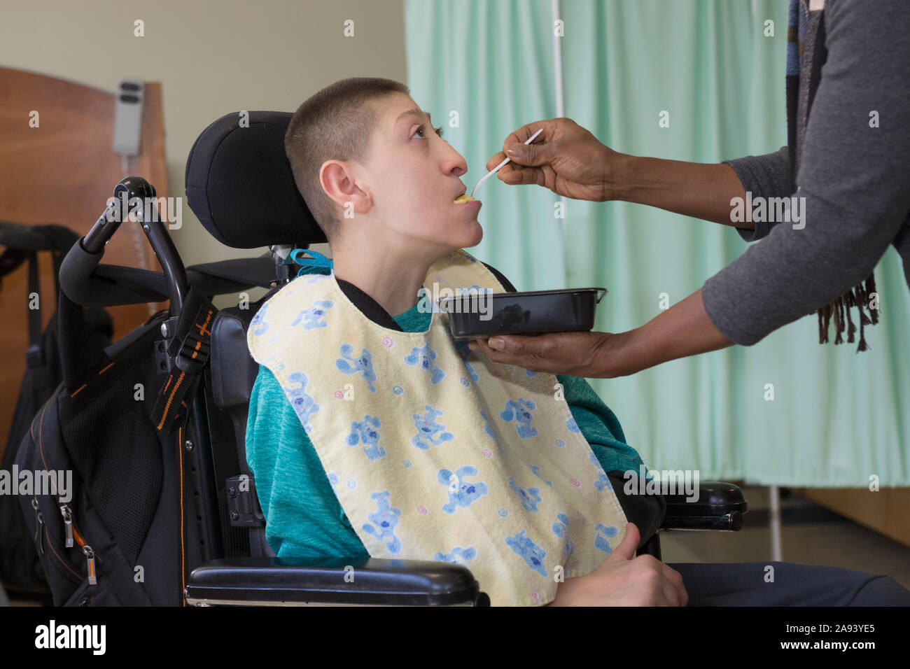 Teen mit Holoprosencephaly wird in der Schule gefüttert Stockfoto