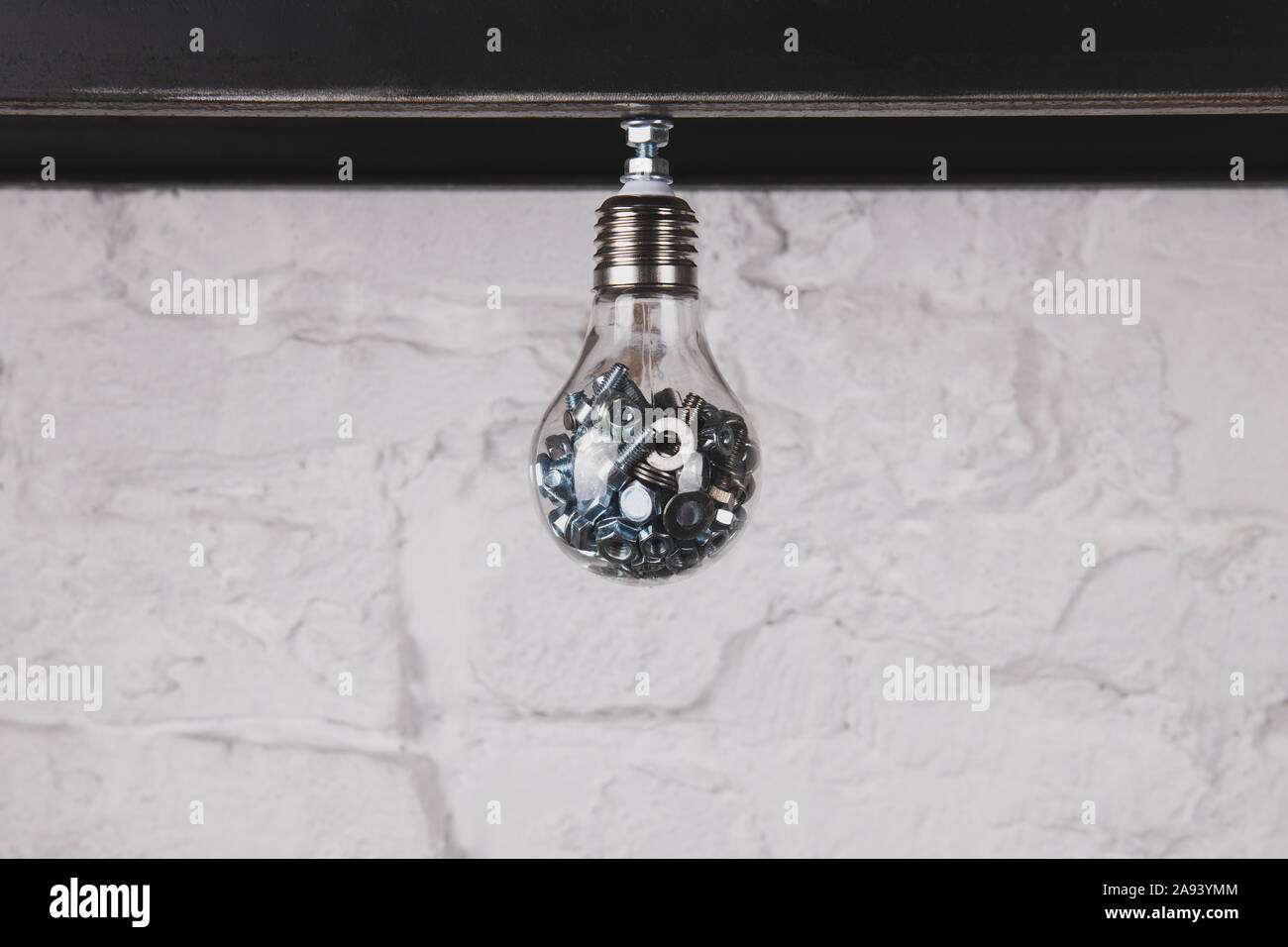 Lampe mit Schrauben und Muttern gegen die weiße Wand. Handgefertigte ungewöhnliche Objekt. Ideen sammeln Konzept Foto. Kreative Person Konzept. Stockfoto