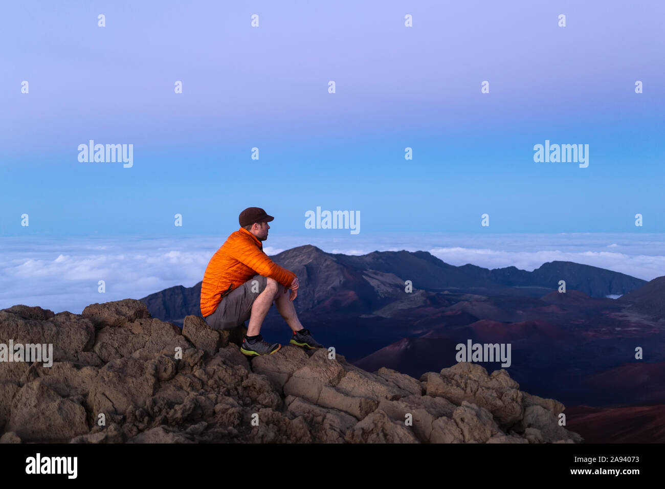 Tourist sitzt auf einem Berggipfel mit Blick auf Haleakala; Maui, Hawaii, Vereinigte Staaten von Amerika Stockfoto