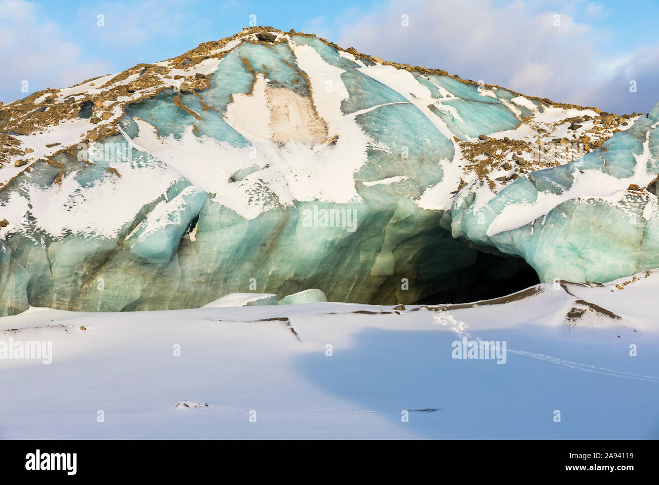 Spuren führen in die dunkle Öffnung eines Tunnels unter dem Eis des Black Rapids Glacier; Alaska, USA Stockfoto