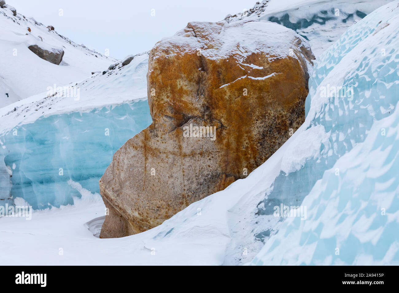 Ein großer Felsbrocken lehnt sich im Winter gegen das Eis des Black Rapids Glacier; Alaska, Vereinigte Staaten von Amerika Stockfoto