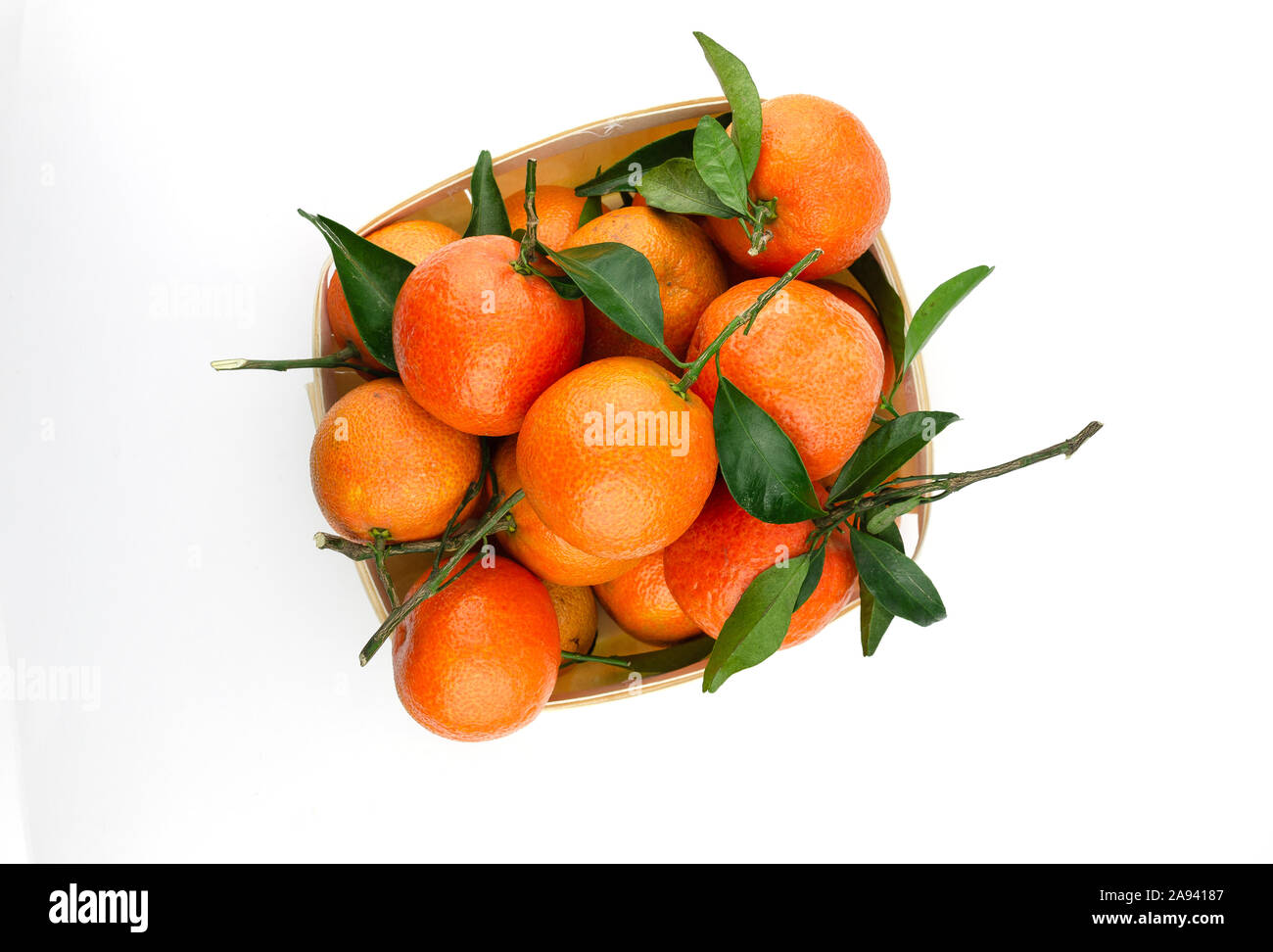 Besonders süß und saftig spanische Clementinen mit Blättern in einem Korb. Auf weiß isoliert. Von oben nach unten anzeigen. Stockfoto