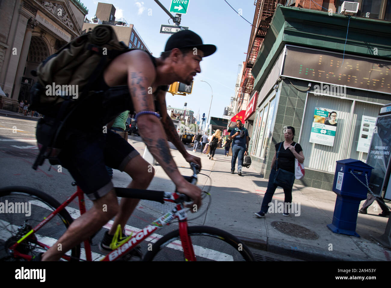 Eine tätowierte Bike courier Geschwindigkeiten über Bowery in New Yorks Chinatown Stockfoto