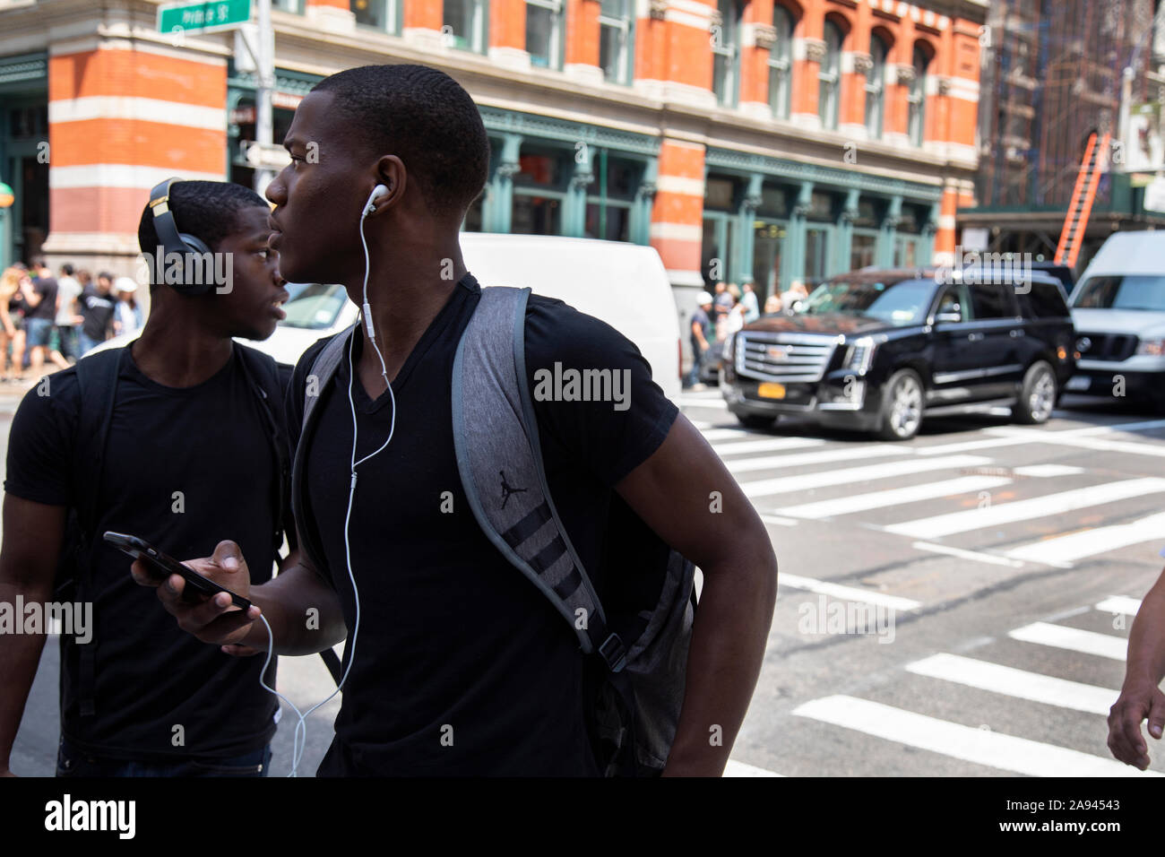 Zwei schwarze amerikanische Männer mit Ohrhörer am Broadway, New York zu Fuß Stockfoto