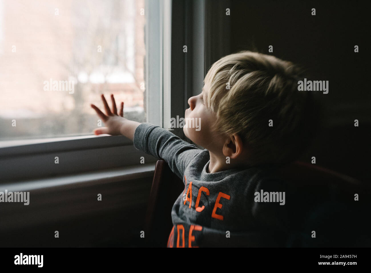 Ein Kleinkind Junge schaut aus dem Fenster. Stockfoto