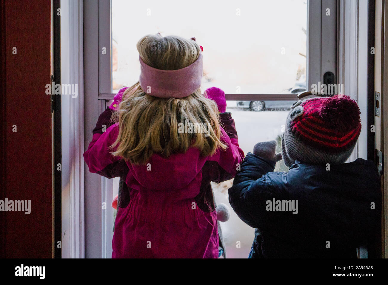 Zwei Kinder im Winter Kleidung aus einer Tür auf Schnee. Stockfoto