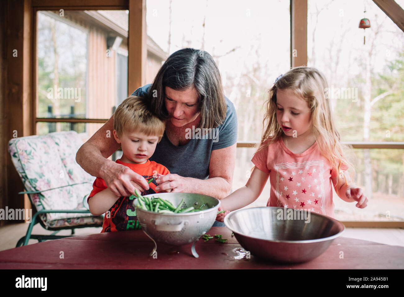 Eine Großmutter lehrt ihre Enkelkinder zu Snap grüne Bohnen. Stockfoto