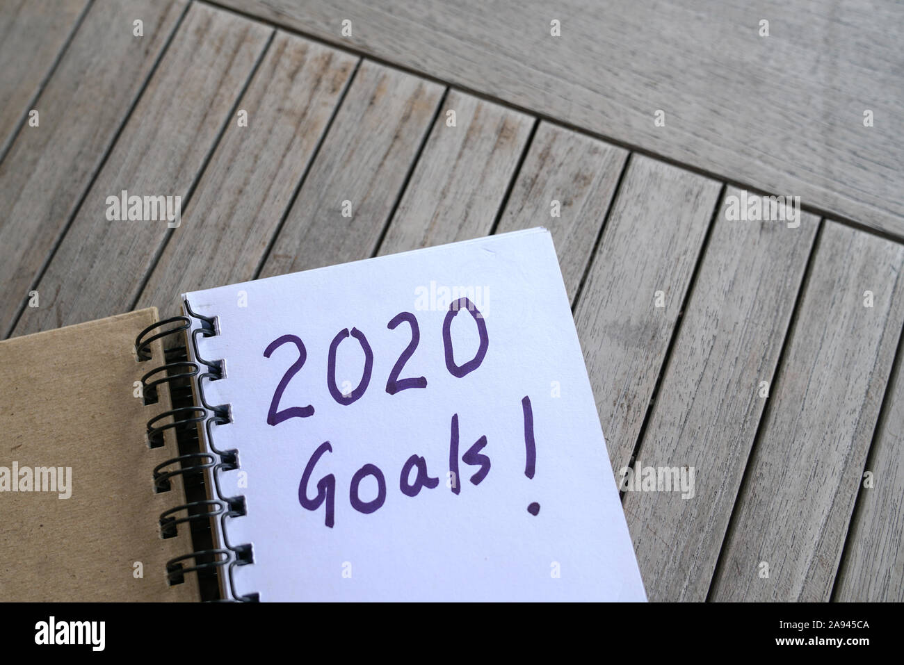 Das neue Jahr 2020. Hand schreiben mit Markierung der 2020-Ziele auf Notepad. Ansicht von oben. Auf einer hölzernen Tisch. Stockfoto
