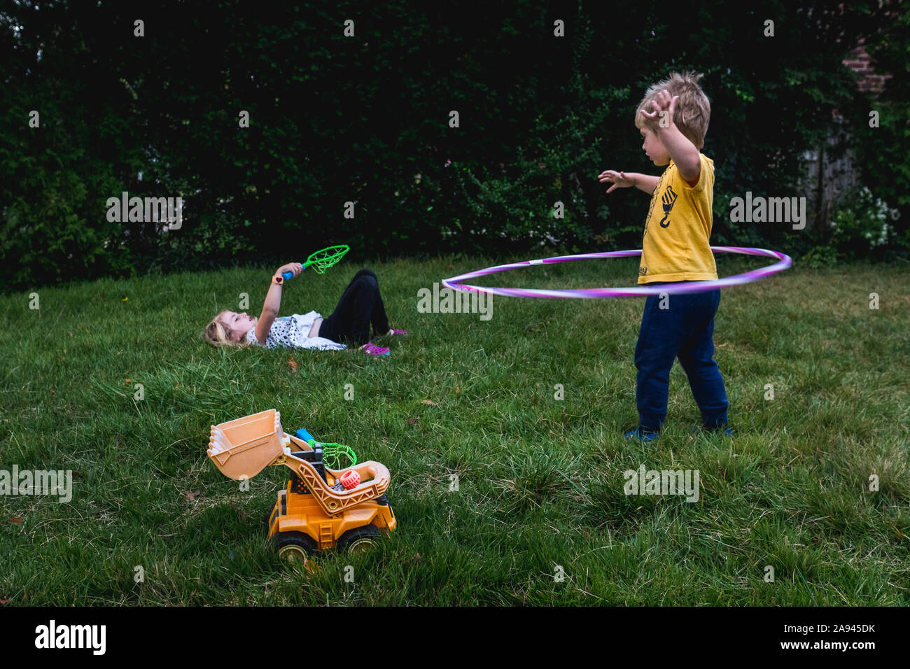 Ein Junge und ein Mädchen spielen mit Spielzeug auf dem Rasen. Stockfoto