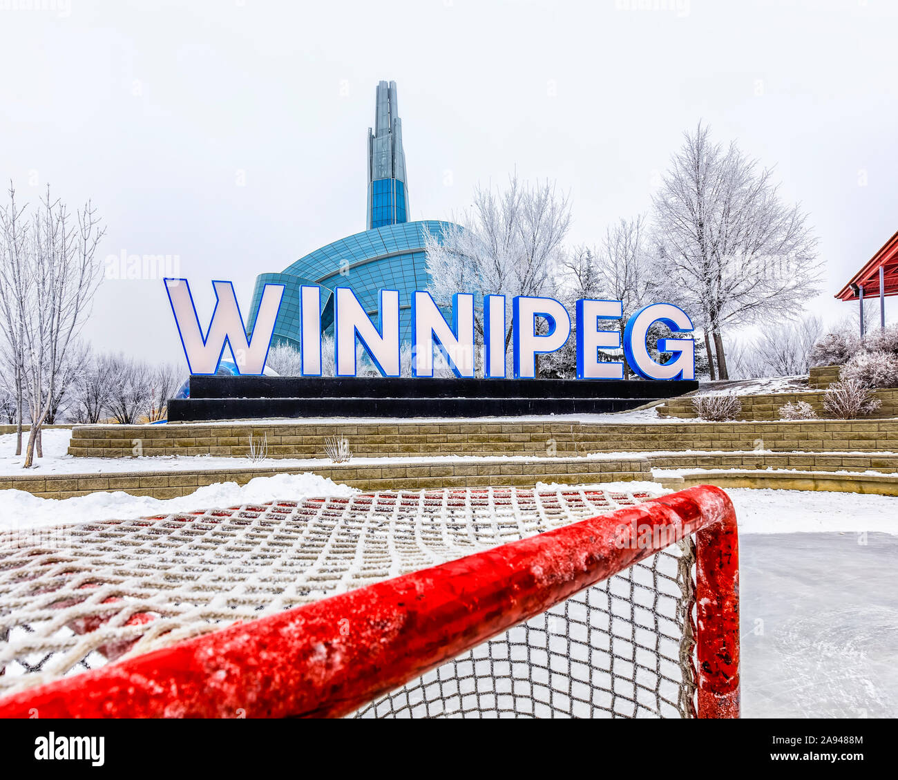 Das Winnipeg-Schild und das Canadian Museum for Human Rights an einem frostigen Wintertag, von der Eishockeybahn an den Forks aus gesehen Stockfoto