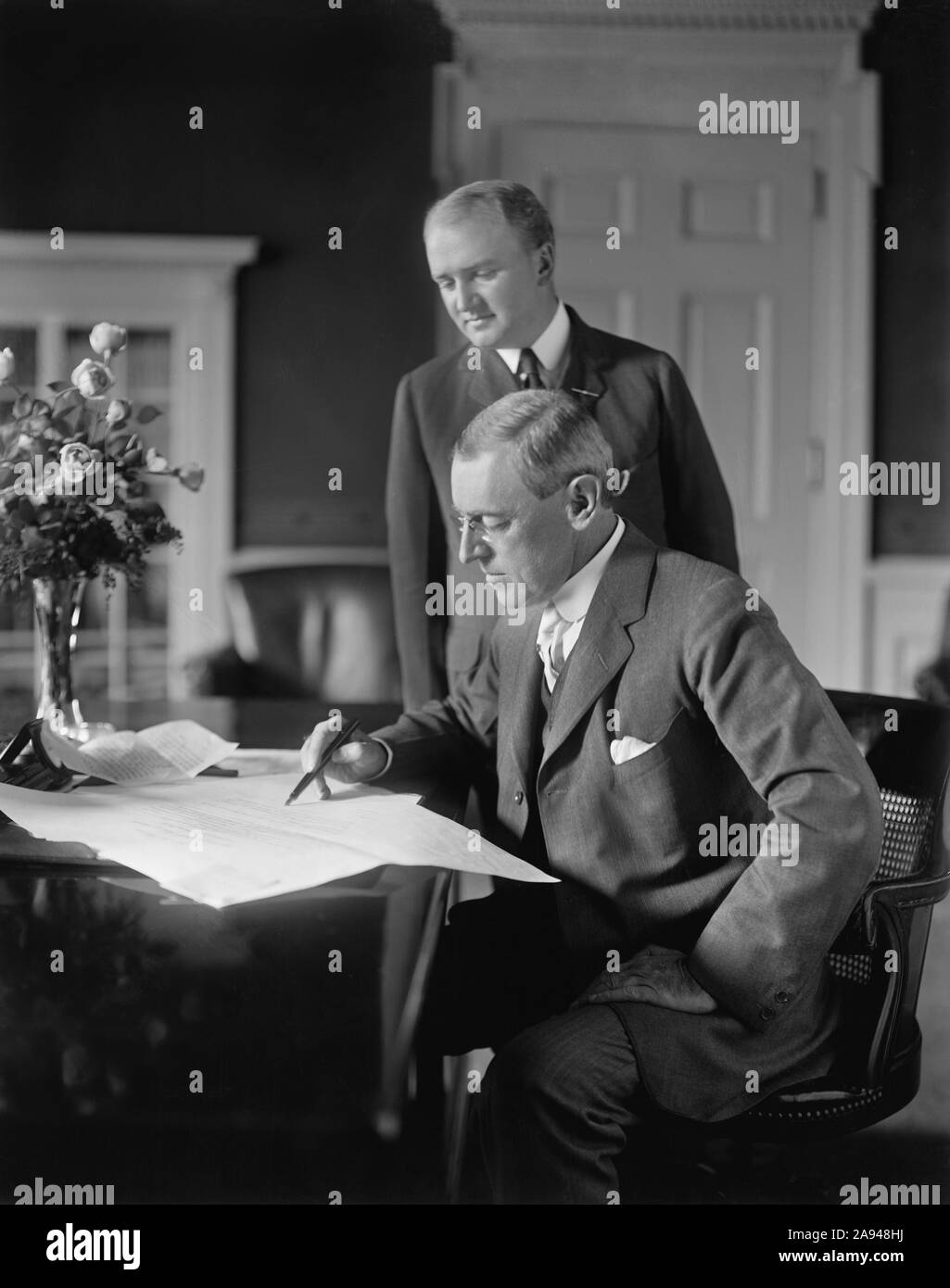 Us-Präsident Woodrow Wilson sitzt am Schreibtisch im Oval Office des Weißen Hauses mit seinem Privatsekretär Joseph Patrick Tumulty standen während Wilson der erste Term in Office, Washington, D.C., USA, Harris & Ewing, zwischen 1913 und 1916 Stockfoto