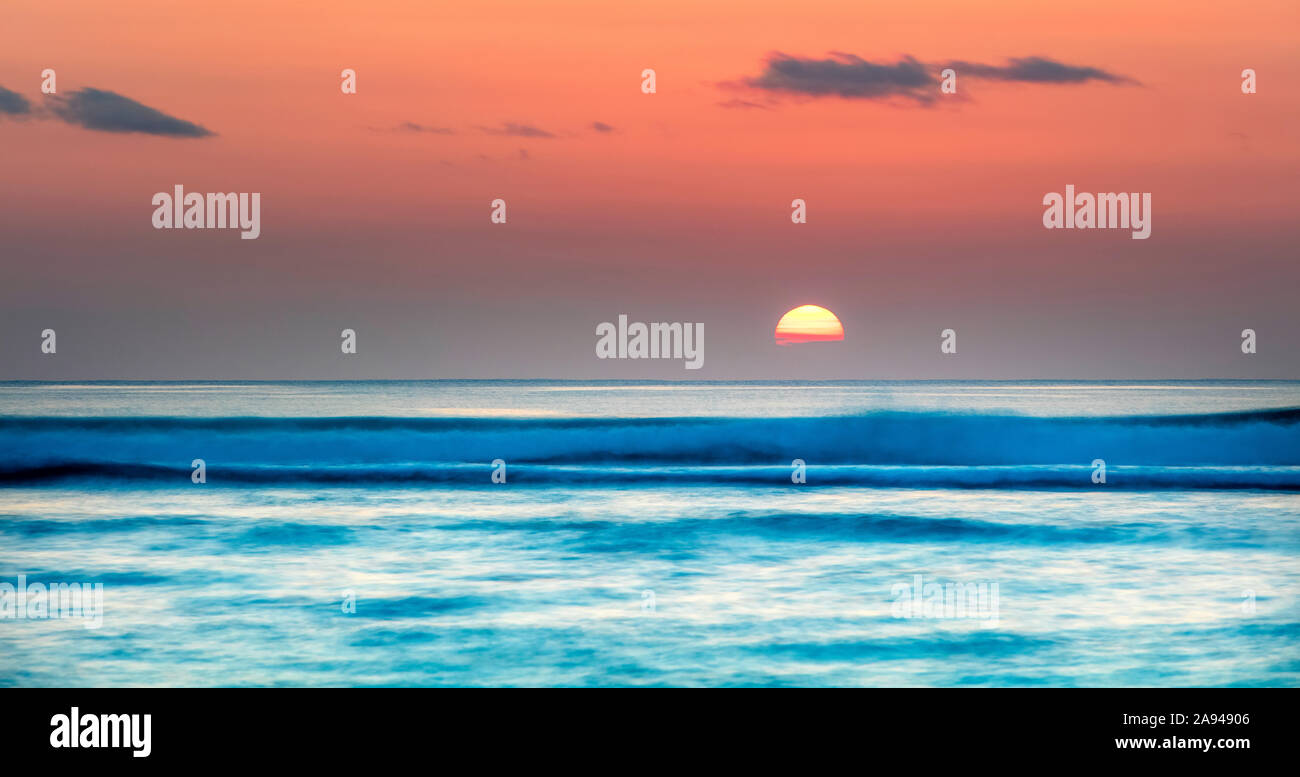 Sinkende Sonne über dem Horizont des Ozeans mit weichen Wellen; Kauai, Hawaii, Vereinigte Staaten von Amerika Stockfoto