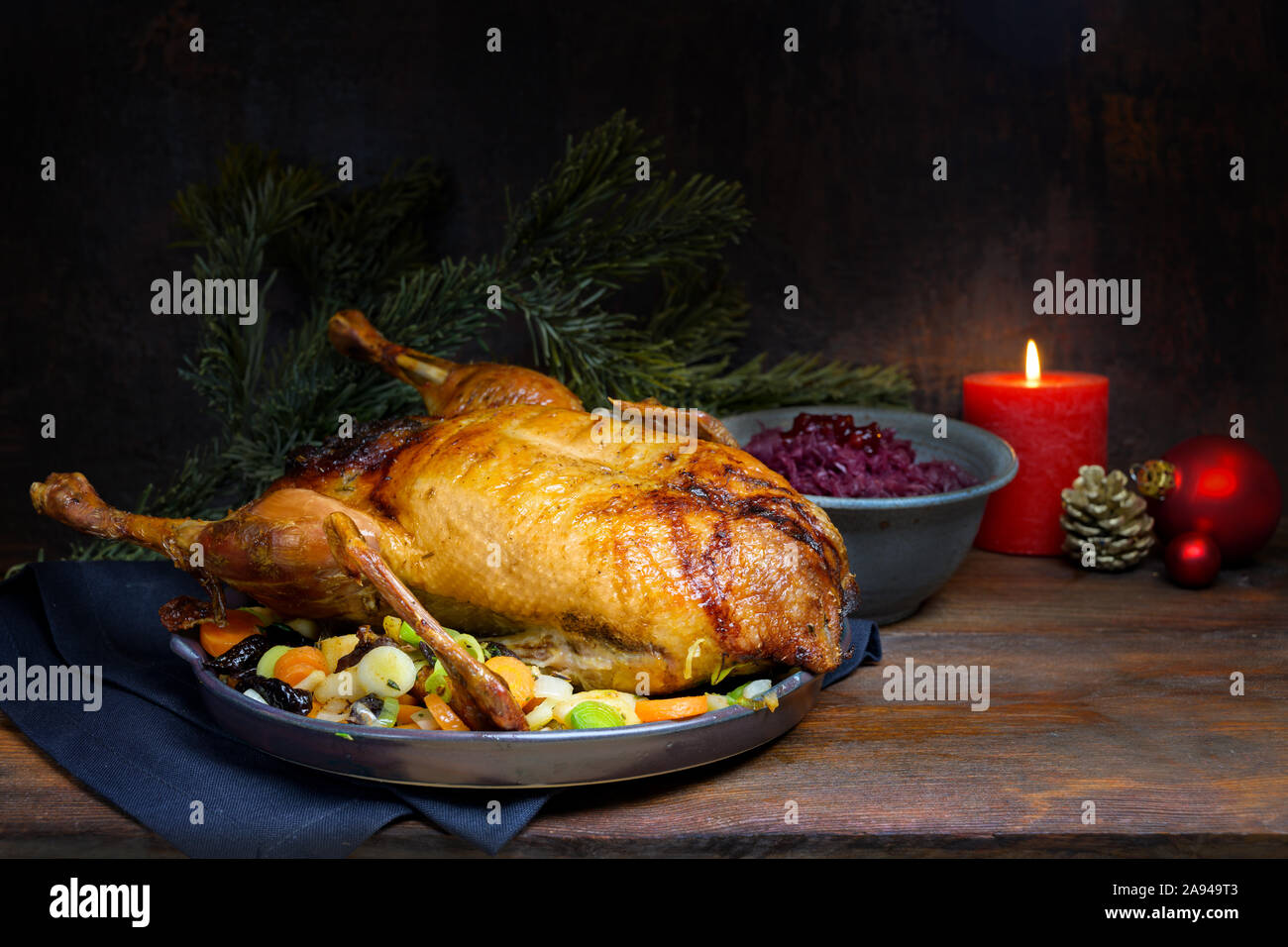 Wie Weihnachten Menü gebratene Ente mit Rotkohl und Gemüse, eine festliche Mahlzeit auf einem rustikalen Holztisch mit brennenden Kerzen und Dekoration, Dunkelbraun Stockfoto