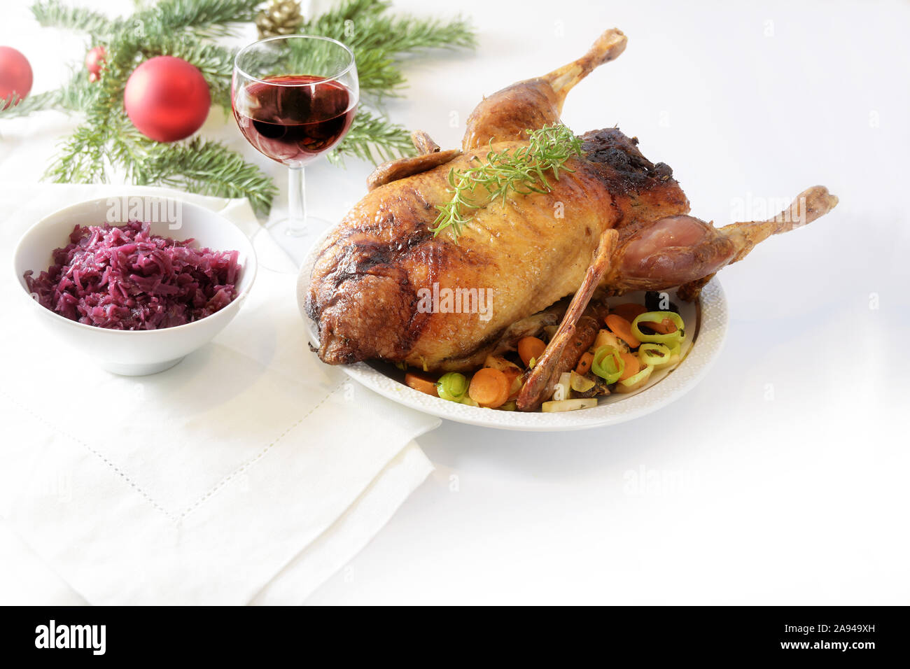 Gebratene ganze Ente mit Gemüse, Rotkohl und Wein auf einem weißen Tisch mit Weihnachtsdekoration, Kopie, ausgewählte konzentrieren Stockfoto
