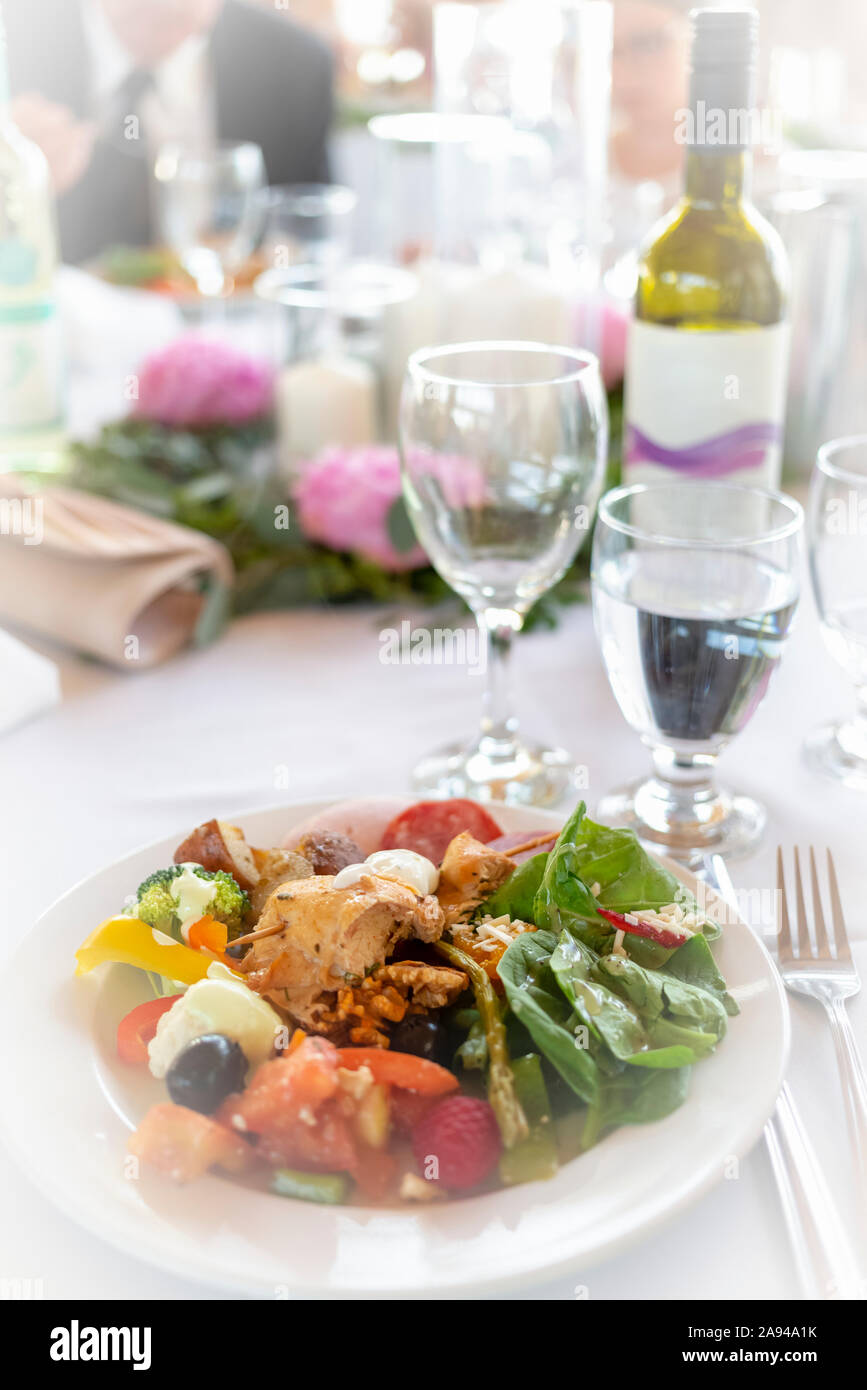 Formeller Tisch bei einer Hochzeit mit Teller voller Speisen und Weinflasche mit Weingläsern; British Columbia, Kanada Stockfoto