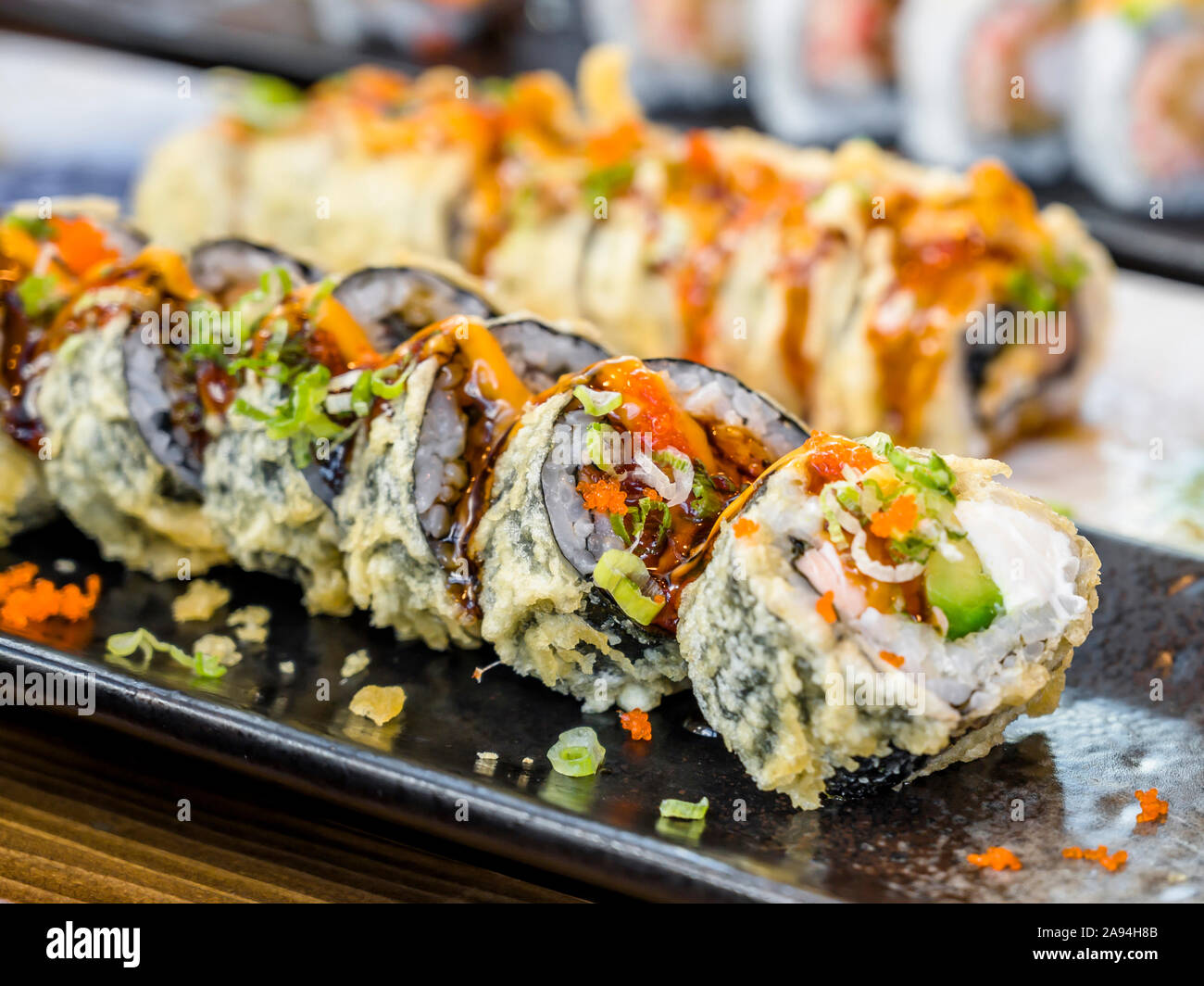 Platten mit verschiedenen Arten von fachmännisch zubereitet und in Scheiben geschnittenen Sushi mit Gewürzen und Saucen sind auf Esstisch köstlich und diätetische zu genießen angezeigt Stockfoto