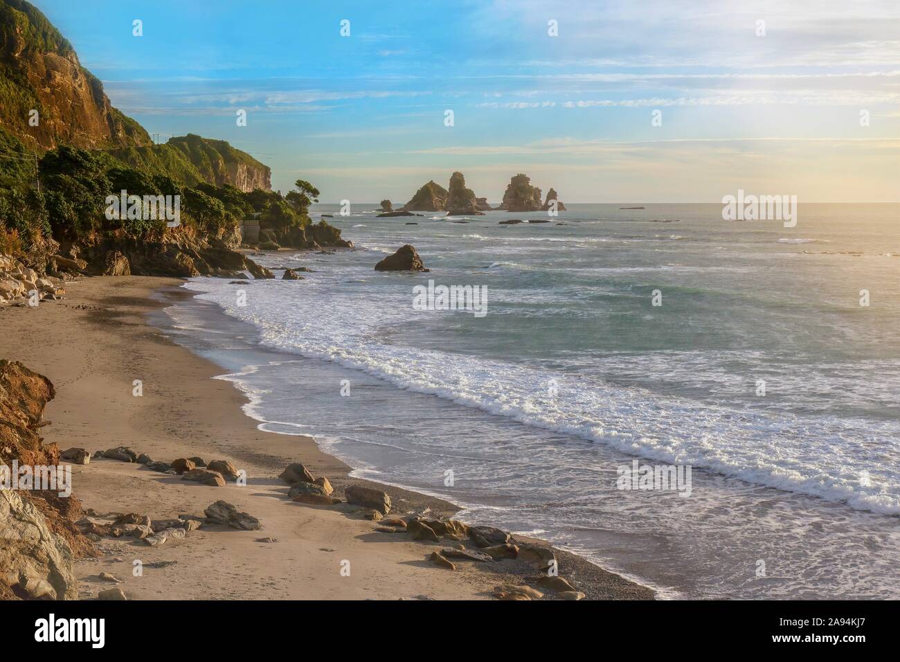 Die Tasmanische See und einem wunderschönen einsamen Strand mit dramatischen Felsformationen, an der Westküste der Südinsel von Neuseeland, bei Sonnenuntergang. Stockfoto