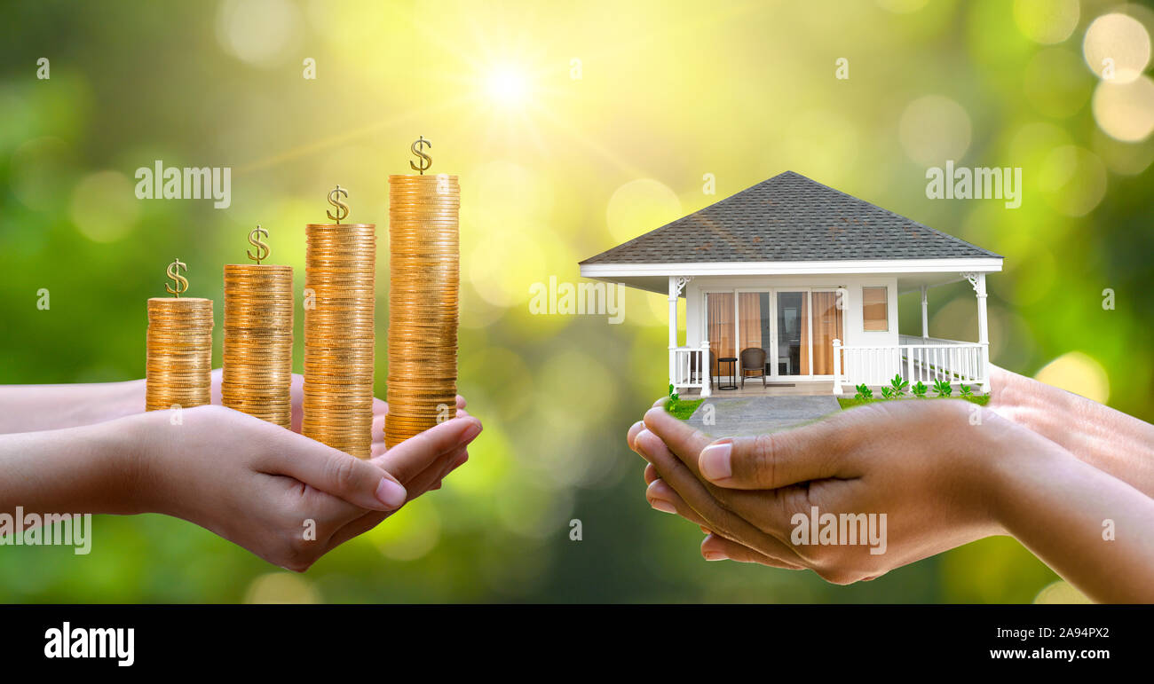 Die Hände eines Kaufmanns Geld und die andere Hand hält ein Haus. Die Idee, Geld zu sparen, um ein Haus zu kaufen Stockfoto