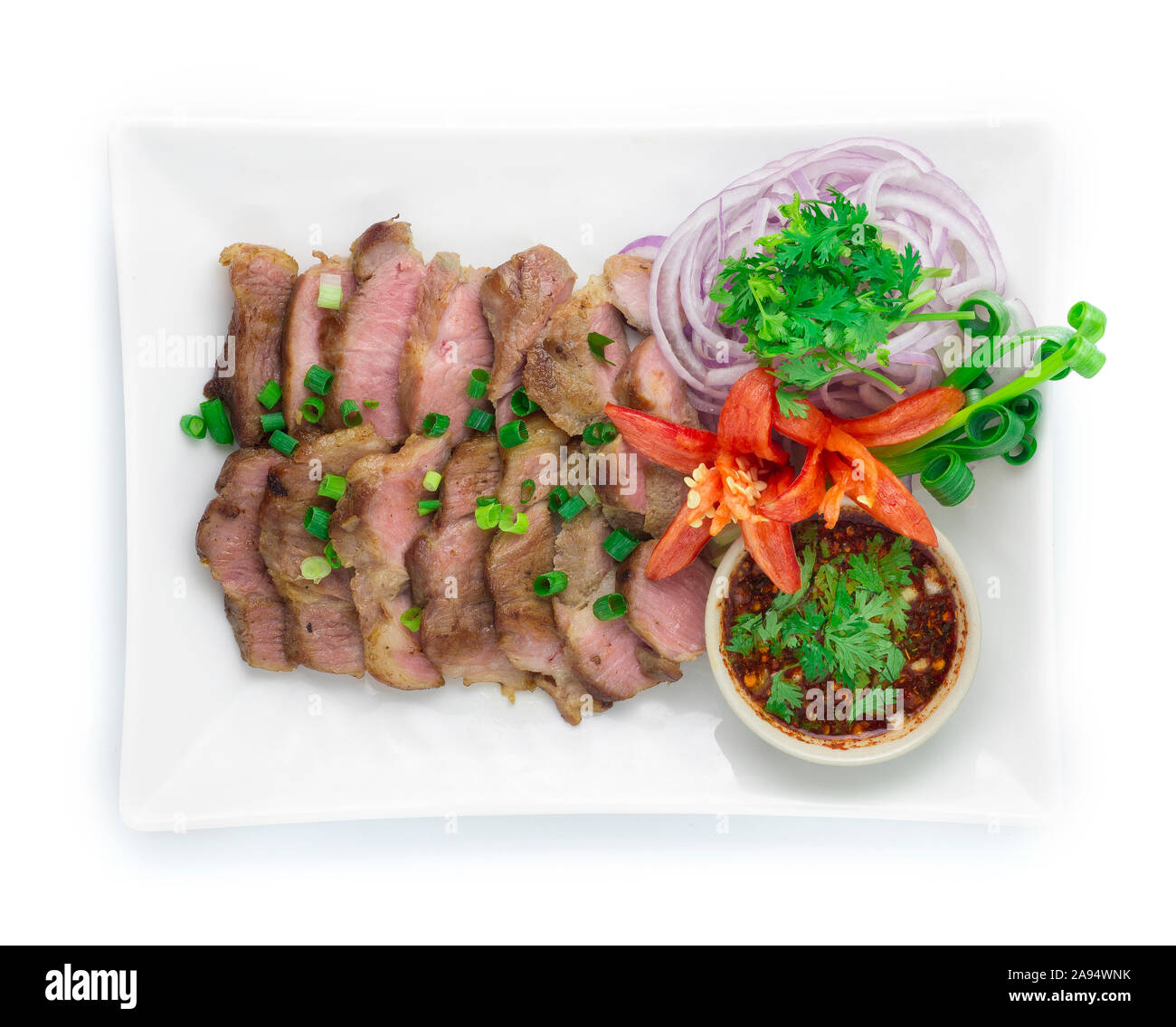 Gegrilltes Schweinefleisch Schichten serviert würzige Soße Nordosten Essen Stil von Thailand dekorieren mit geschnitzten Paprika, Gurke, Tomate, Gemüse, Ansicht von oben Stockfoto