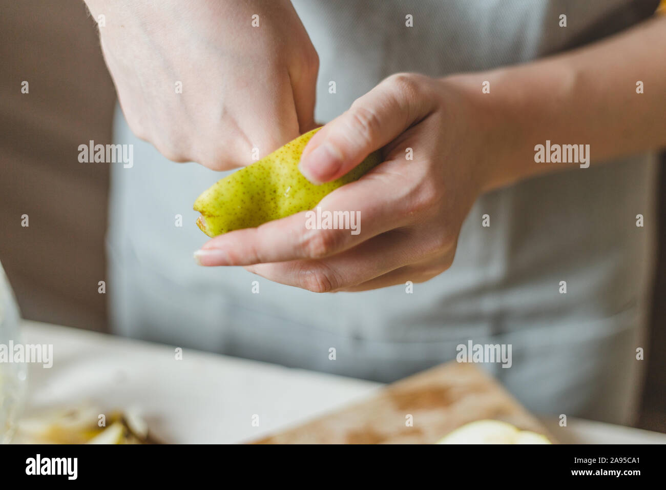 Schneiden Birnen in einem Salat auf einem Holzbrett - selbstgemachtes Rezept - der Hausfrau Hände - Ländliche Stockfoto