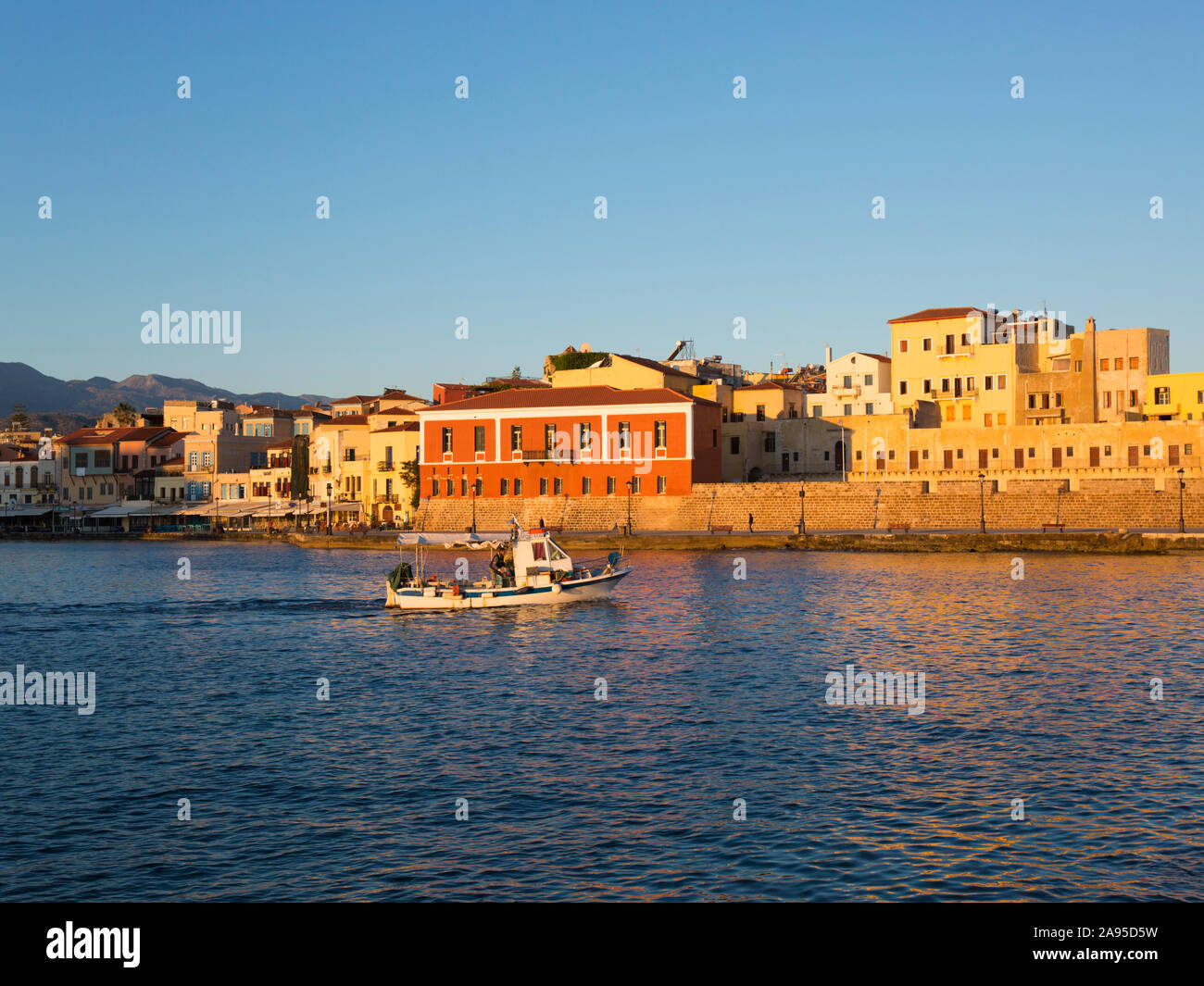 Chania, Kreta, Griechenland. Blick über den venezianischen Hafen bei Sonnenaufgang, Fischerboot auf dem Weg zum Meer. Stockfoto