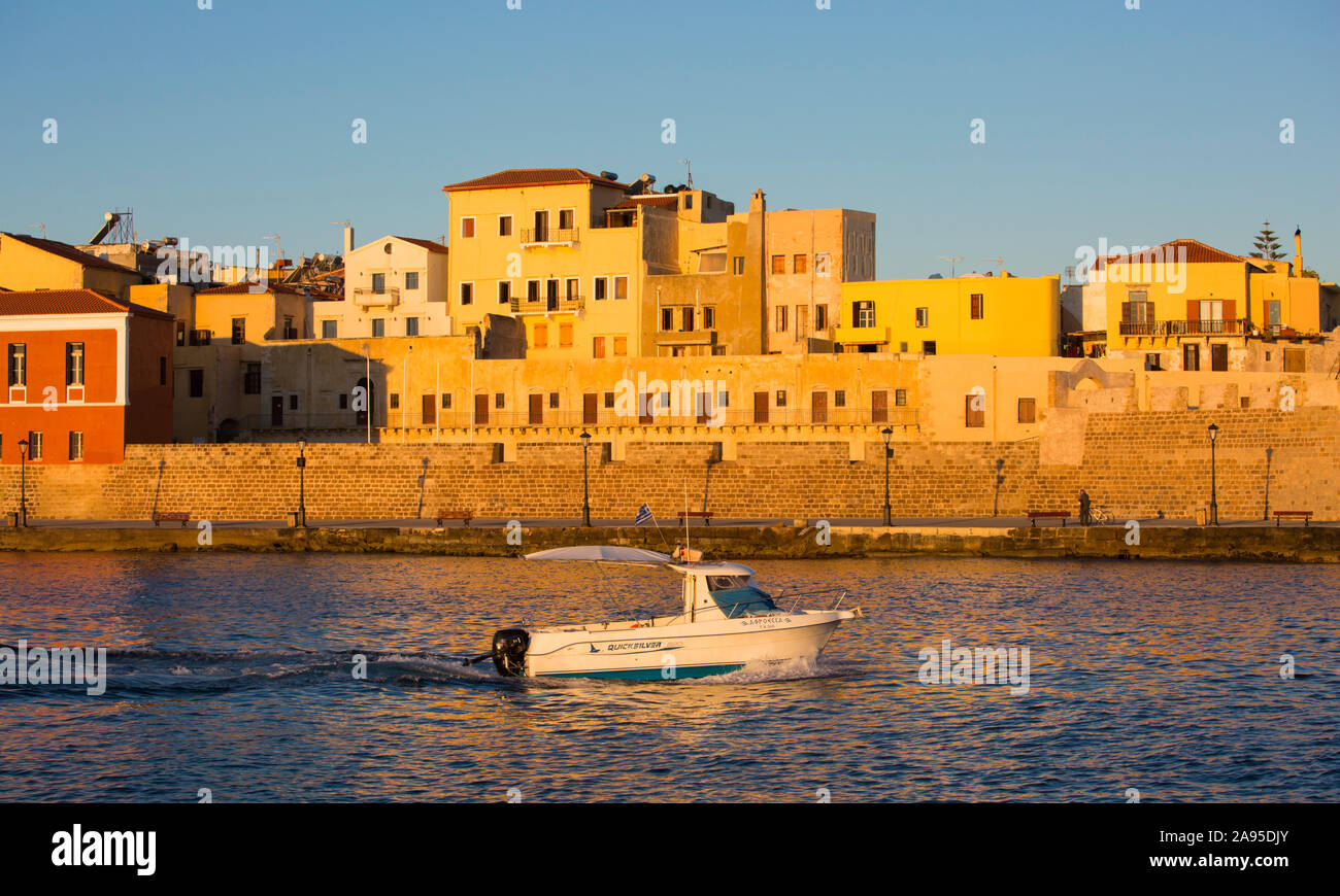 Chania, Kreta, Griechenland. Blick über den venezianischen Hafen bei Sonnenaufgang, kleines Boot auf dem Weg zum Meer. Stockfoto