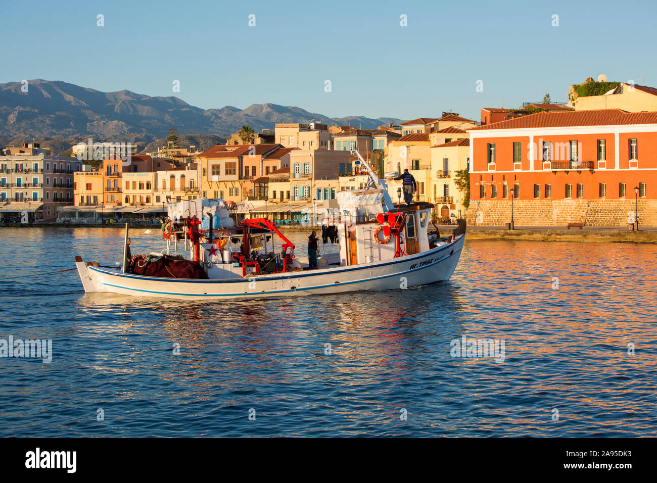Chania, Kreta, Griechenland. Blick über den venezianischen Hafen bei Sonnenaufgang, Fischerboot auf dem Weg zum Meer. Stockfoto