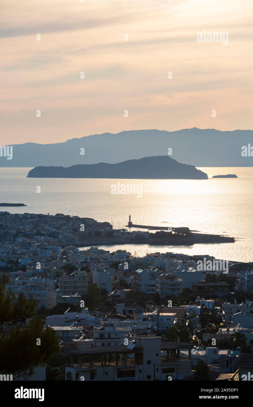 Chania, Kreta, Griechenland. Hintergrundbeleuchteter Blick über die Stadt und den Golf von Chania, Abend, die Insel Agii Theodori prominent. Stockfoto