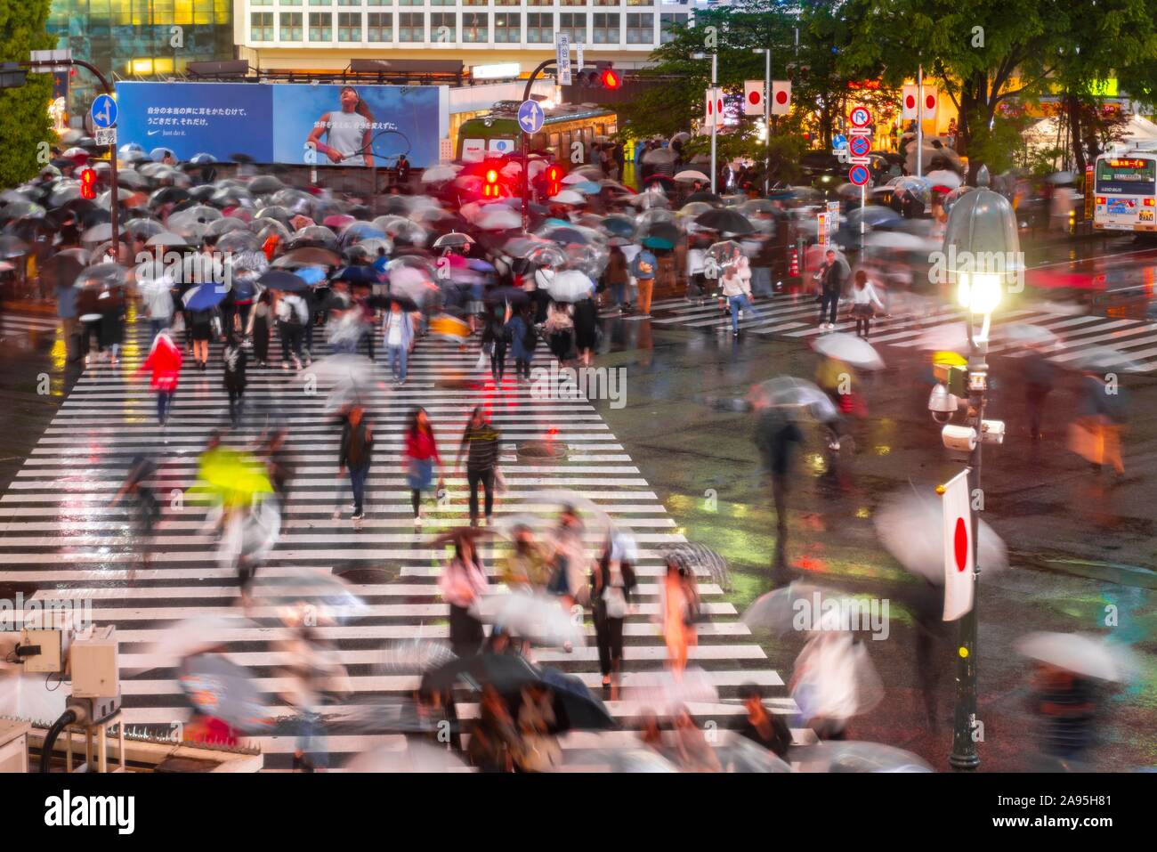 Masse mit Sonnenschirmen auf Zebrastreifen nachts, Kreuzung Shibuya Crossing, Shibuya, Tokio, Japan Stockfoto