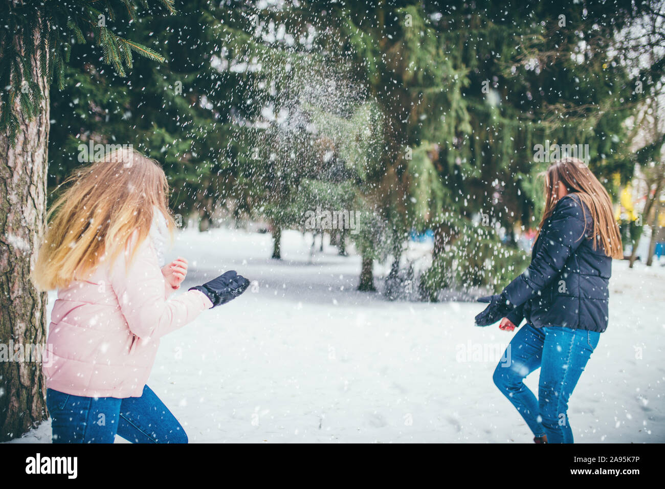 Zwei junge Freundinnen Spaß und genießen im Winter Wald mit Lächeln Schnee werfen - Lebensstil Stockfoto