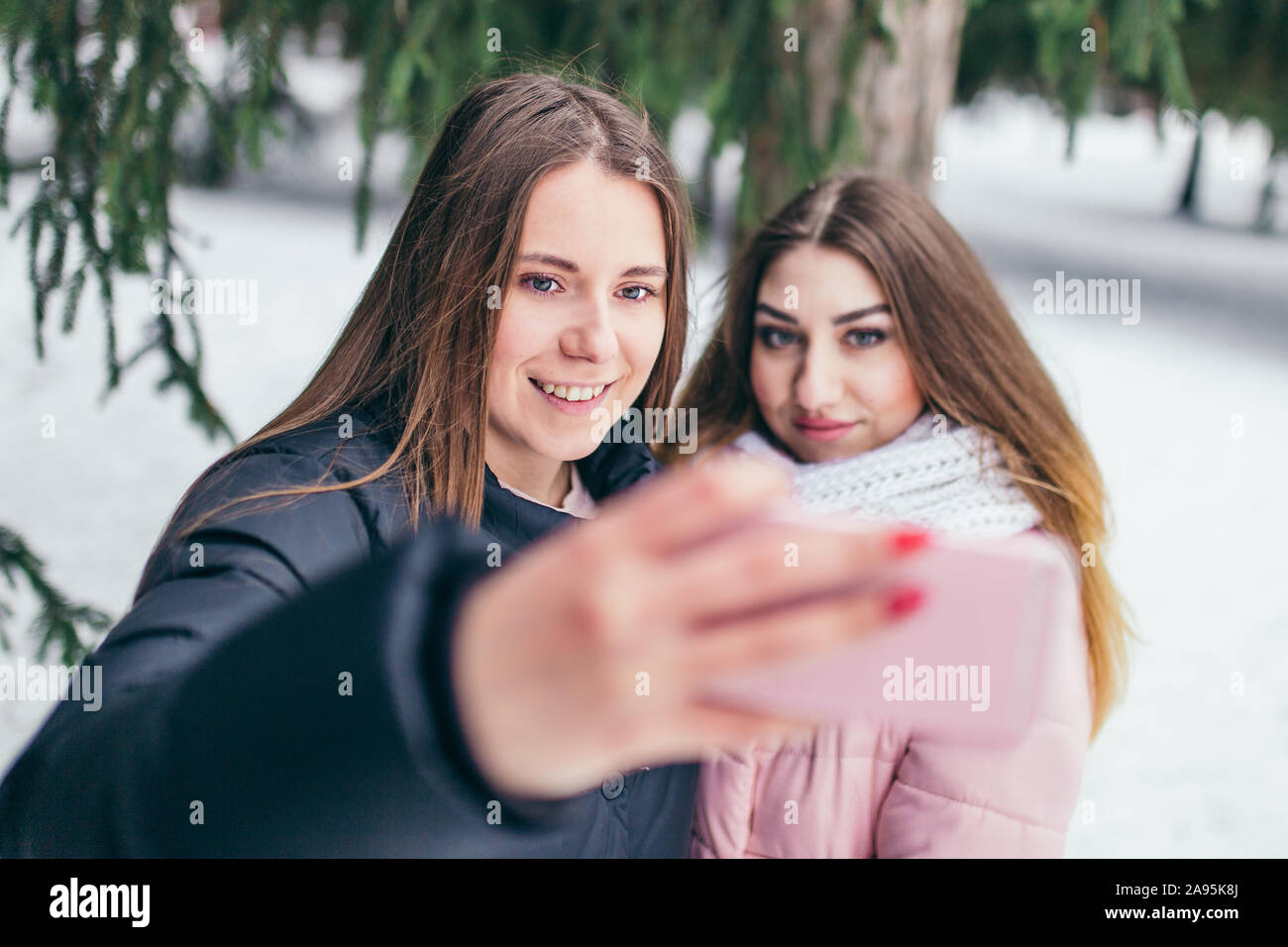 Zwei junge fröhliche Freundinnen unter selfie im Winter außerhalb - Lebensstil Stockfoto