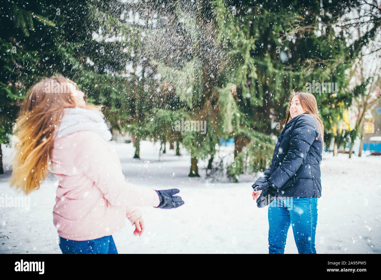 Abschied von der Kindheit - zwei junge Freundinnen werfen Schneebälle im Winter Wald Stockfoto