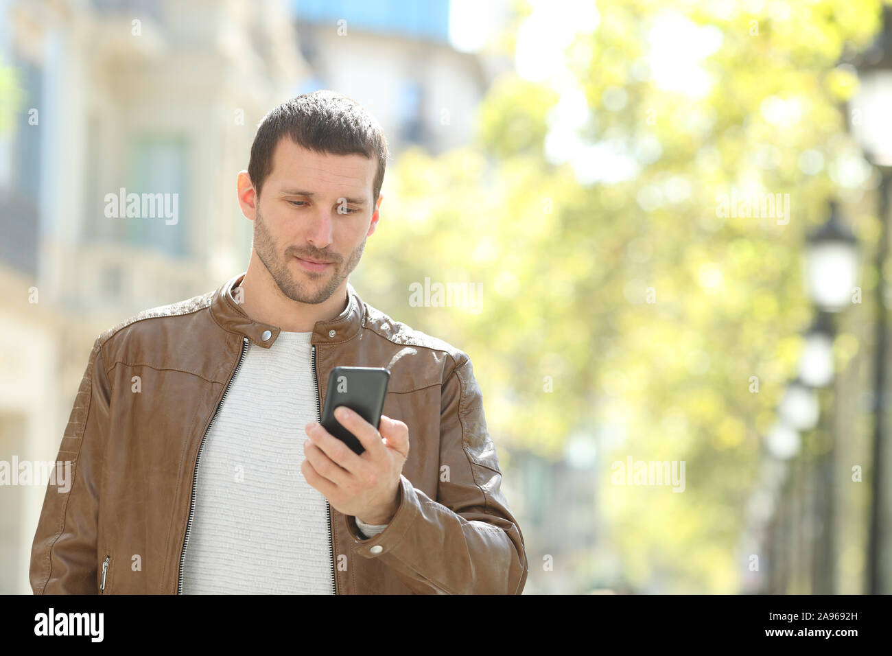Schwere erwachsenen Mann Kontrolle smart phone allein zu Fuß auf der Straße Stockfoto
