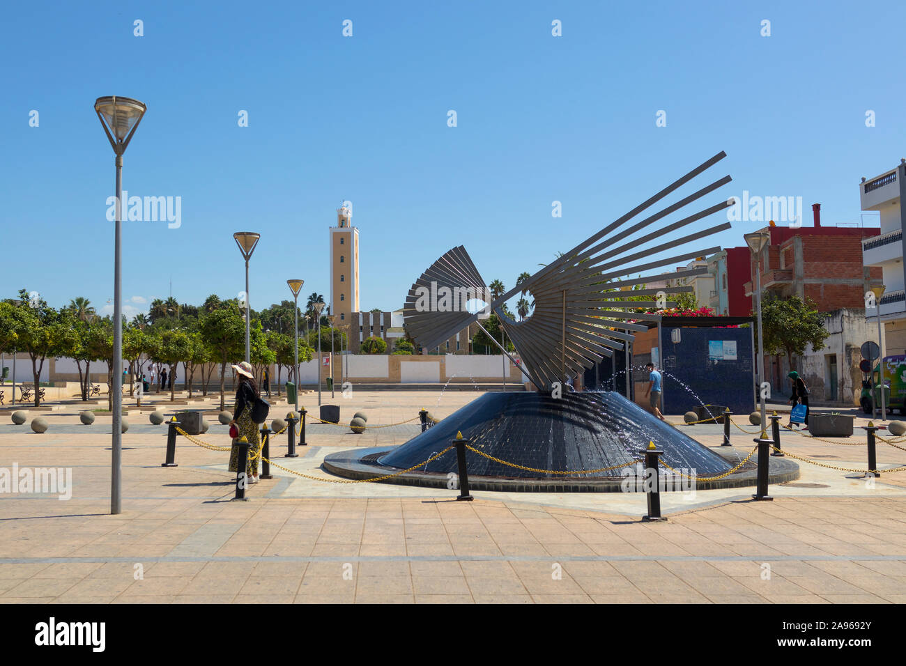 Asilah, Morocco-September 10, 2019: Dekorative Brunnen bei Zellaka Square in Asilah mit dem Mohamed V Moschee im Hintergrund, Nördliche Marokko Stockfoto