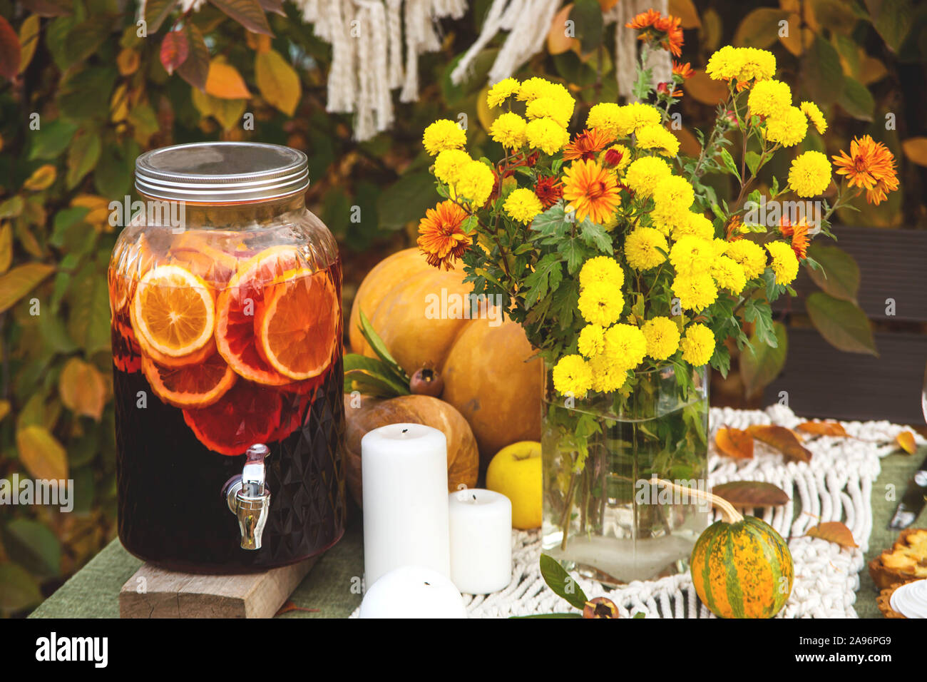 Leuchtend gelbe Chrysanthemen und ein Glas Glühwein Faß auf ein festliches Essen Tisch im Freien. Stockfoto