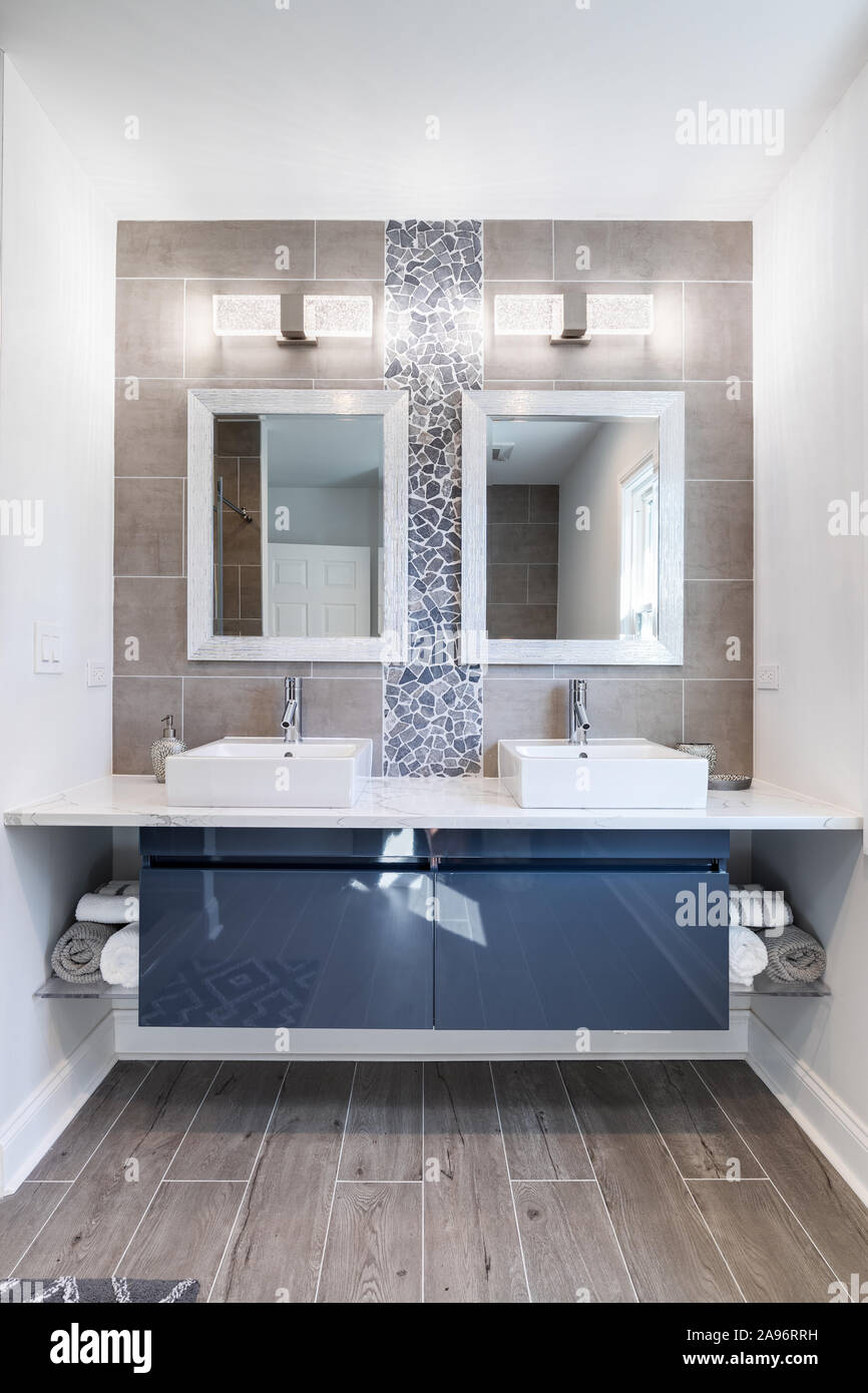 Ein modernes Bad mit einer Blauen Kabinett, Fliesen und Stein zurück Splash, und Marmorfliesen. Ein Platz auf der Seite der Vanity bietet Storage. Stockfoto