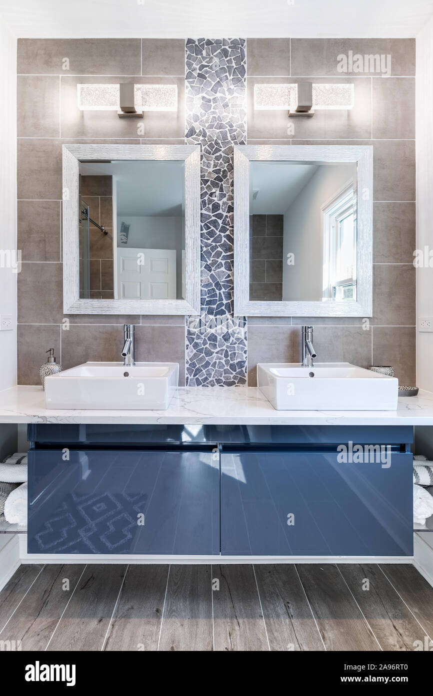Ein modernes Bad mit einer Blauen Kabinett, Fliesen und Stein zurück Splash, und Marmorfliesen. Ein Platz auf der Seite der Vanity bietet Storage. Stockfoto