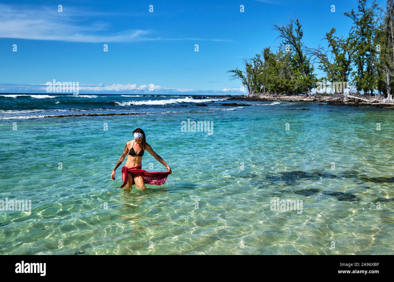 Eine junge Frau geht aus eine flache Lagune, in der Nähe von Makalawena Beach Stockfoto