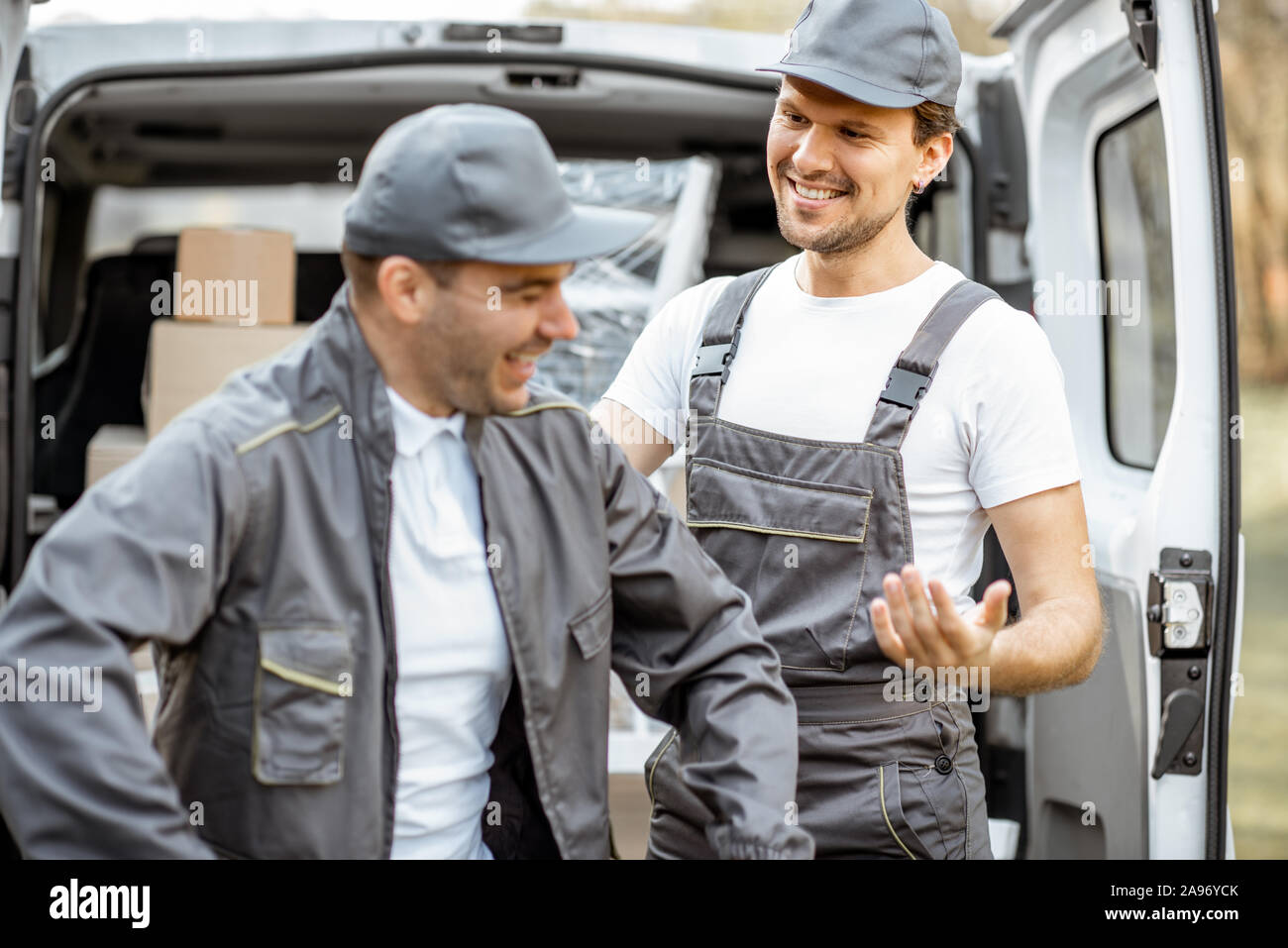 Porträt einer zwei freundliche Lieferung Männer oder movers in  Arbeitskleidung in der Nähe von einer Ladung Fahrzeug Kofferraum voller  Boxen zu liefern Stockfotografie - Alamy