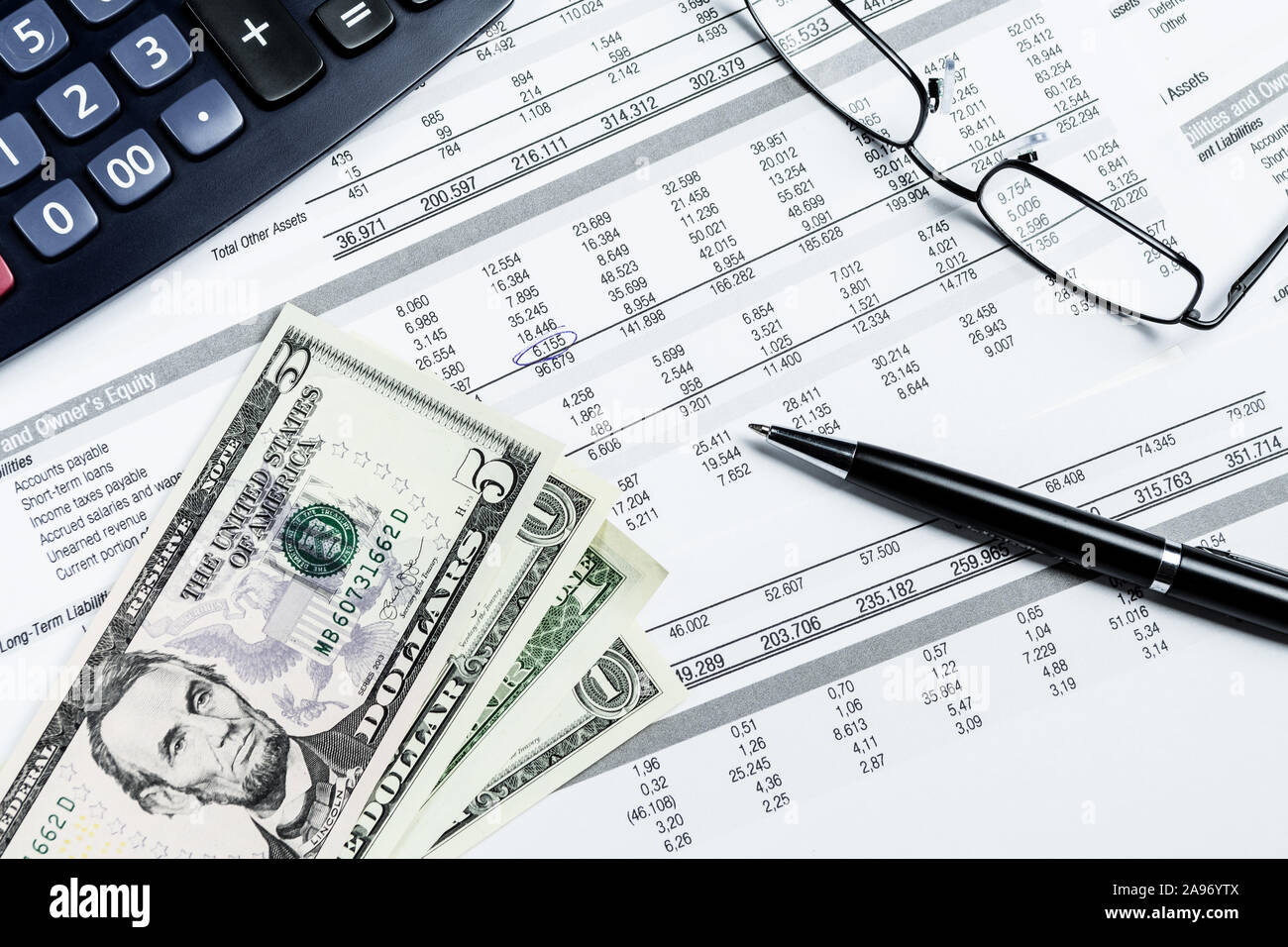 US Dollar Banknoten, Kugelschreiber, Taschenrechner und Brillen auf einen mockup Bilanz. Rechnungswesen, Wirtschaft, Finanzen und Steuern. Stockfoto