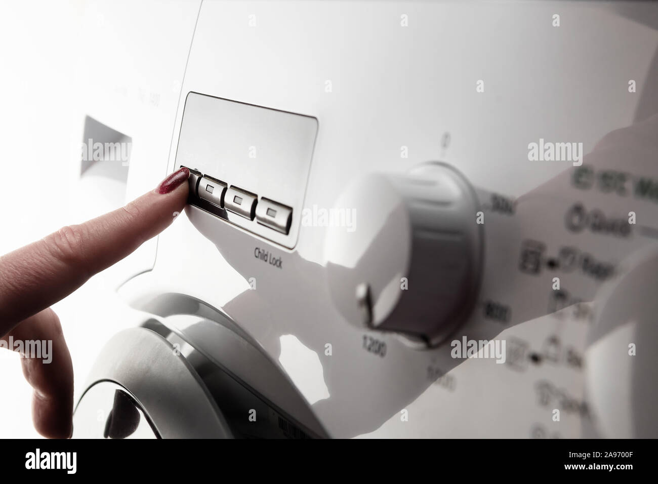 Closeup Detail der Frau Zeigefinger mit Nagellack drücken Taste auf weißes modernes Waschmaschine Stockfoto