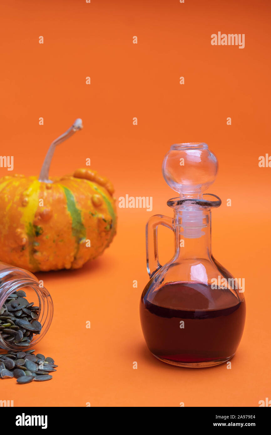 Glas Glas von organischen Kürbiskernöl auf orange Hintergrund Stockfoto