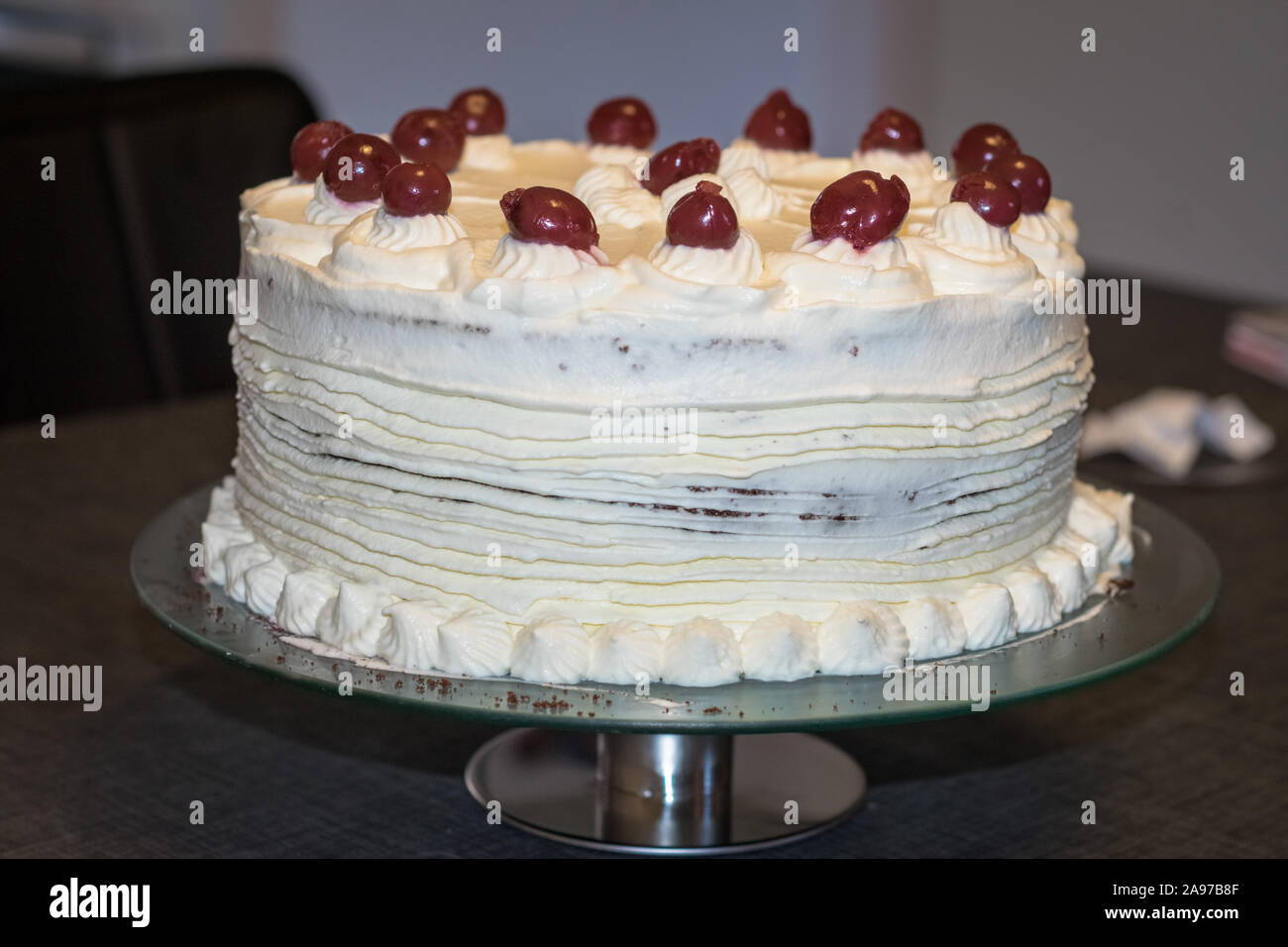 Echte Schwarzwälder Kirschtorte (Schwarzwaelder Boten kirsch Kuchen) mit Sahne und Kirschen auf einem Teller dekoriert Stockfoto