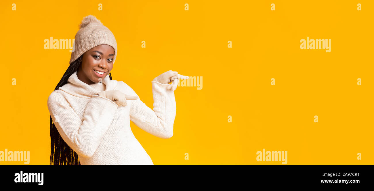Happy African American Girl im Winter Mütze und Handschuhe in der leere Raum, über Gelb studio Hintergrund, Panorama Stockfoto