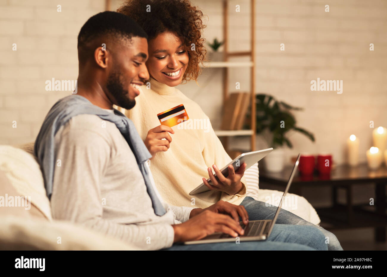 E-Commerce Konzept. Afrikanisch-amerikanisches Paar mit Laptop und Kreditkarte, Dinge online kaufen Stockfoto