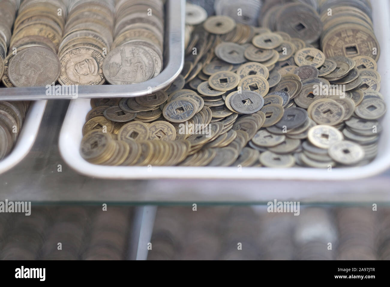 Fächer mit alten Münzen im Fenster einer Antiquitätengeschäft. Vietnam. Stockfoto