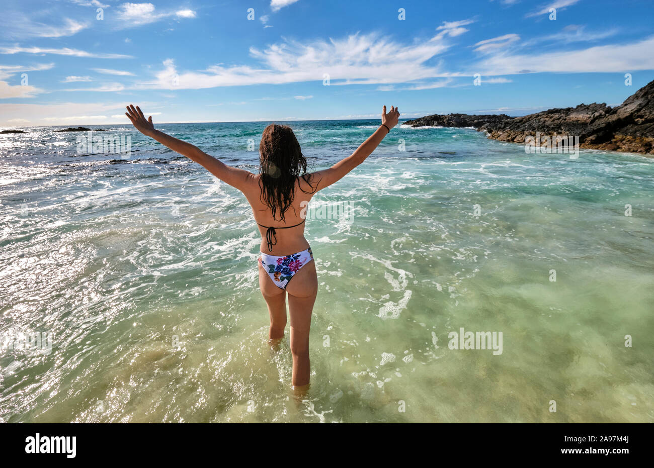 Eine Frau spielt in den Wellen auf Makalawena Beach, Big Island Hawaii Stockfoto